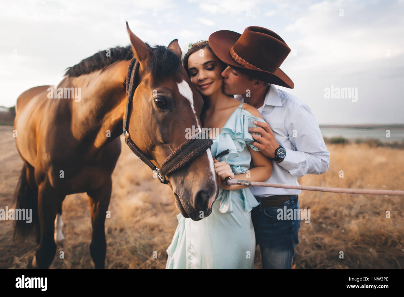 Caucasian cowboy kissing woman on cheek near horse Stock Photo