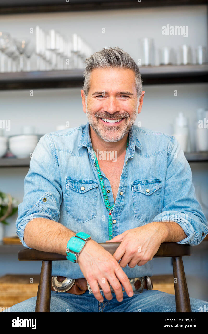 Smiling Caucasian man leaning on chair in store Stock Photo