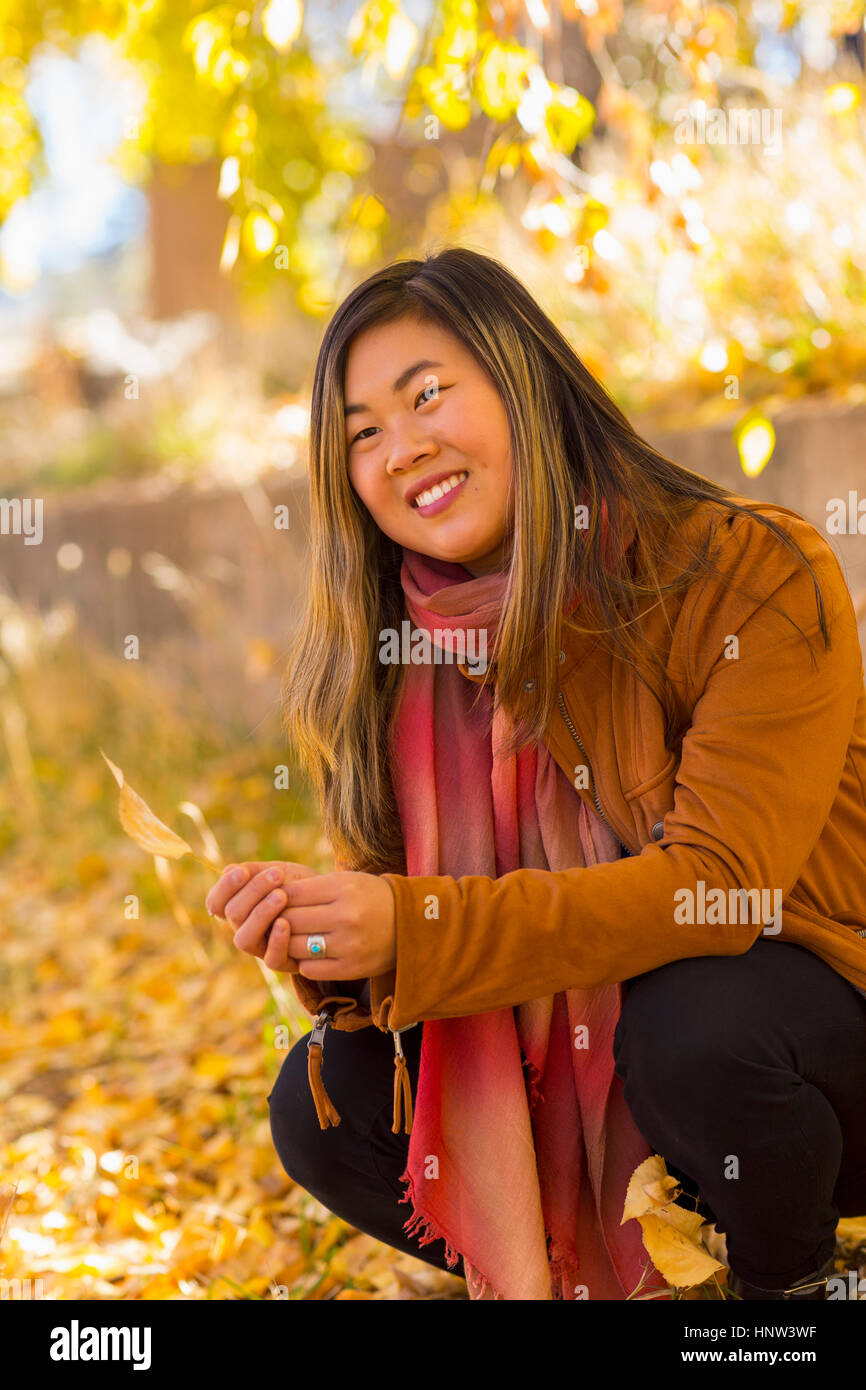 Smiling Asian woman holding leaf in autumn Stock Photo