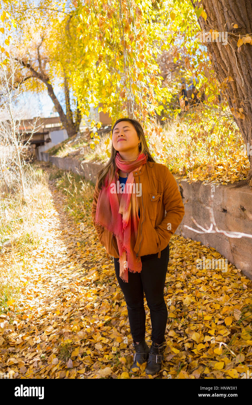 Smiling Asian woman smelling fresh air in autumn Stock Photo