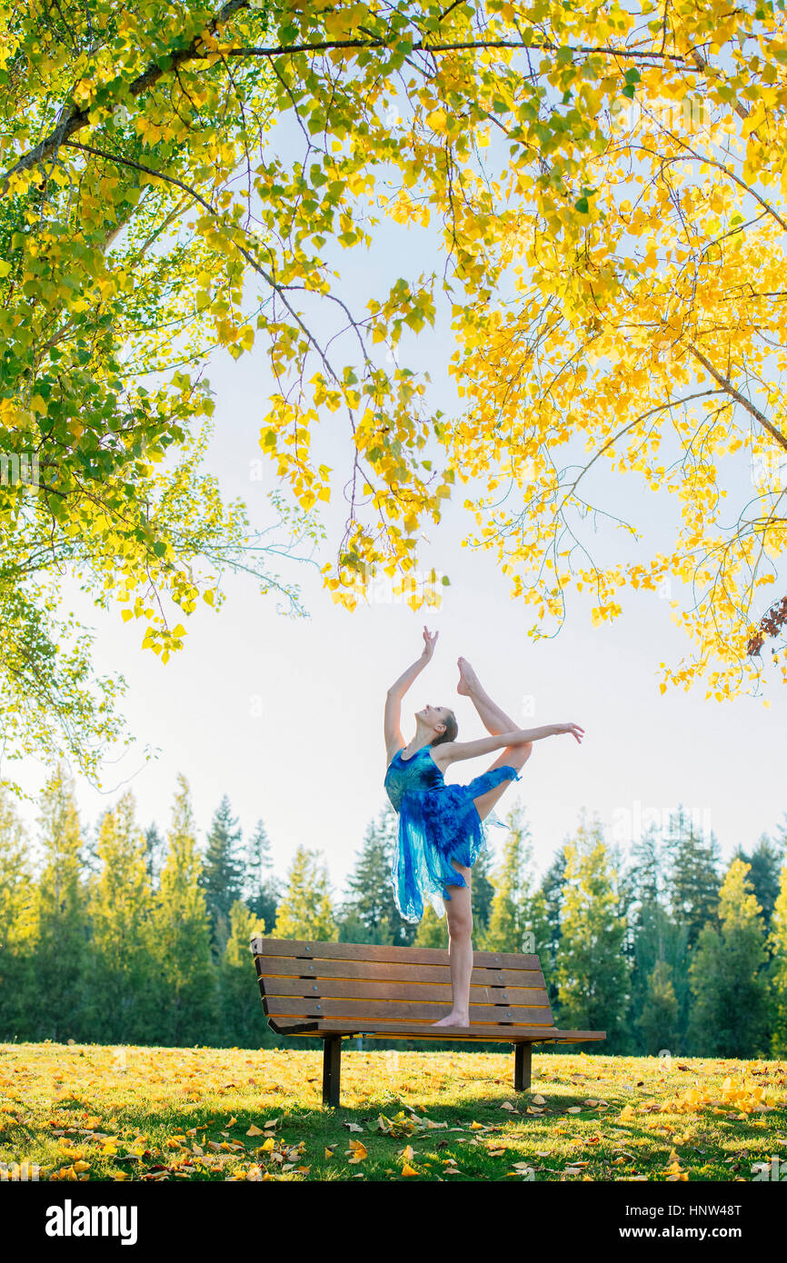 Caucasian ballerina dancing on park bench Stock Photo