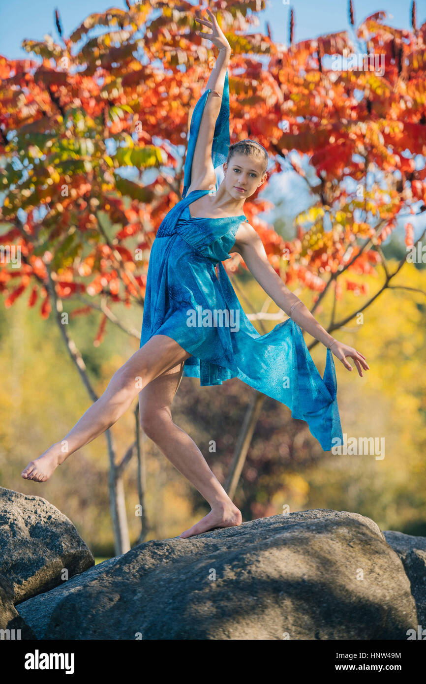 Caucasian ballerina dancing on rocks in park Stock Photo
