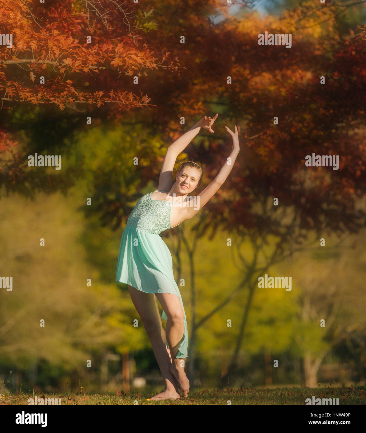 Caucasian ballerina dancing under branches in park Stock Photo