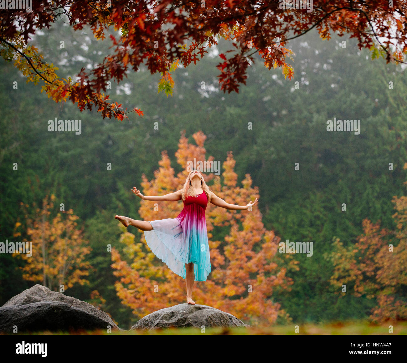 Caucasian ballerina dancing on rock in park Stock Photo