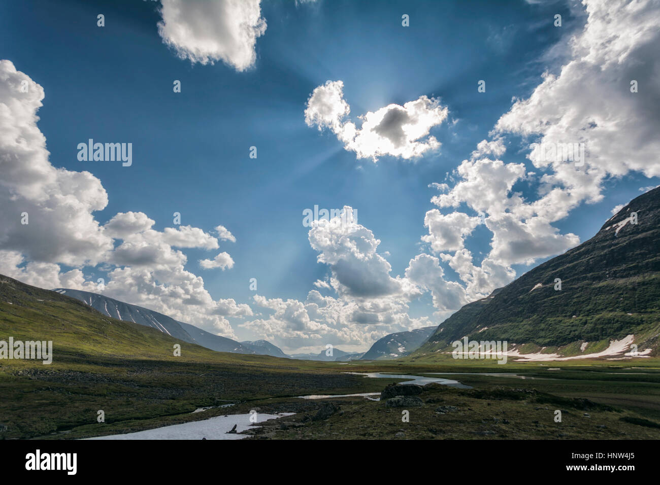 Sunbeams over river in remote valley Stock Photo