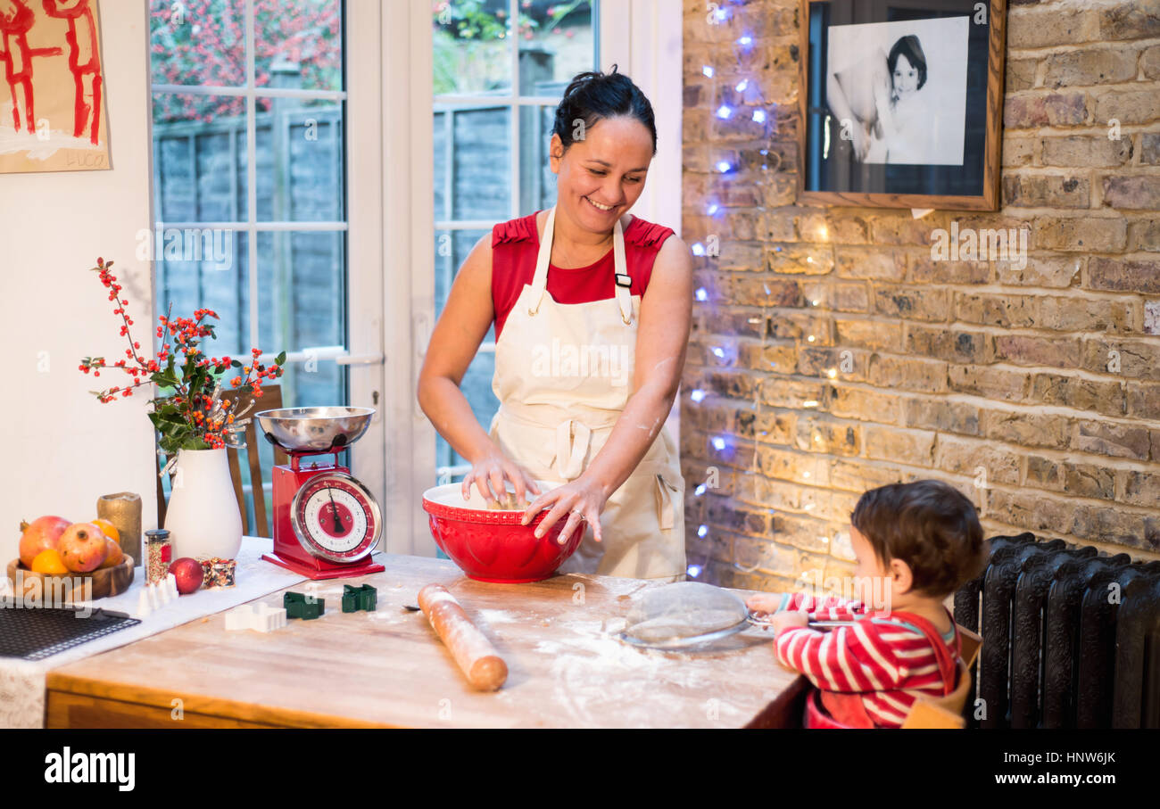 Mother making Christmas cookies, smiling at baby boy Stock Photo