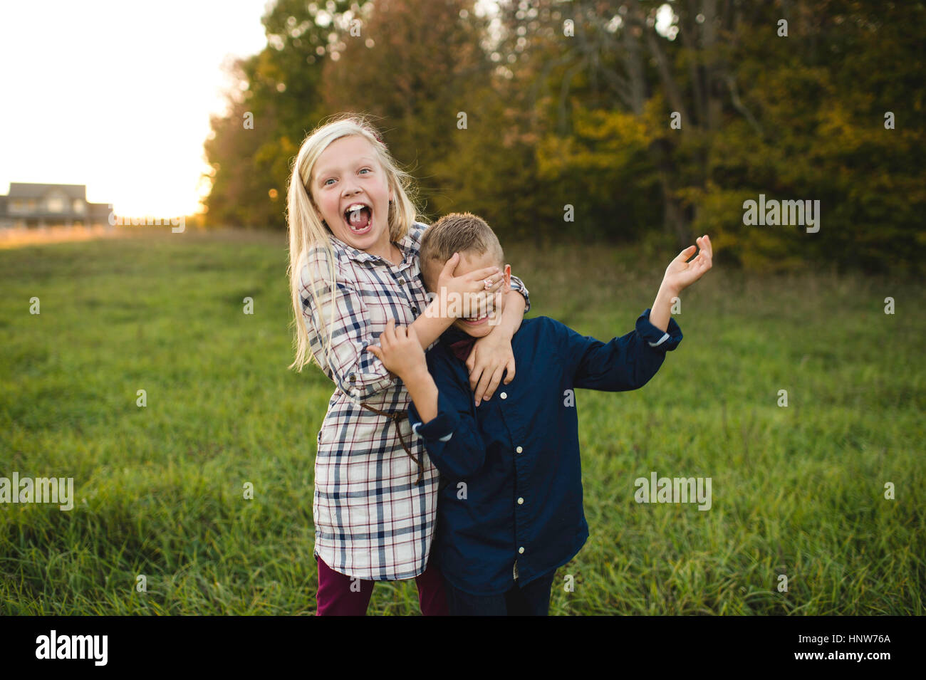 Sister covering brother's eyes smiling Stock Photo