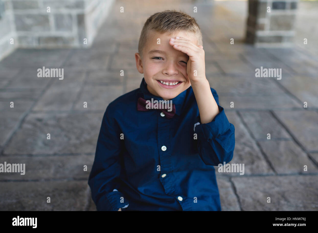 Portrait of boy shielding eyes looking at camera smiling Stock Photo