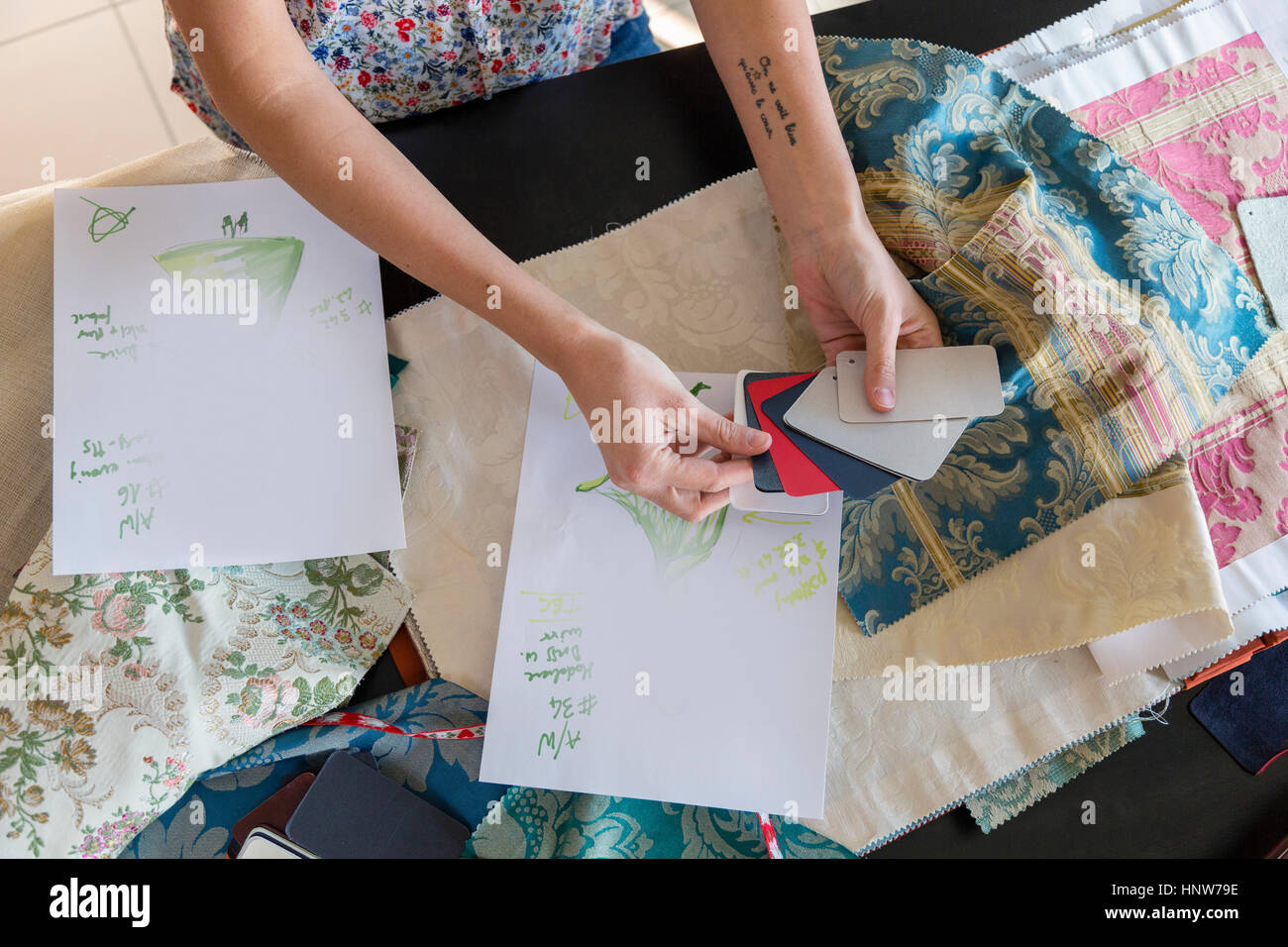 Cropped view of woman at desk looking at swatches and fabric samples ...