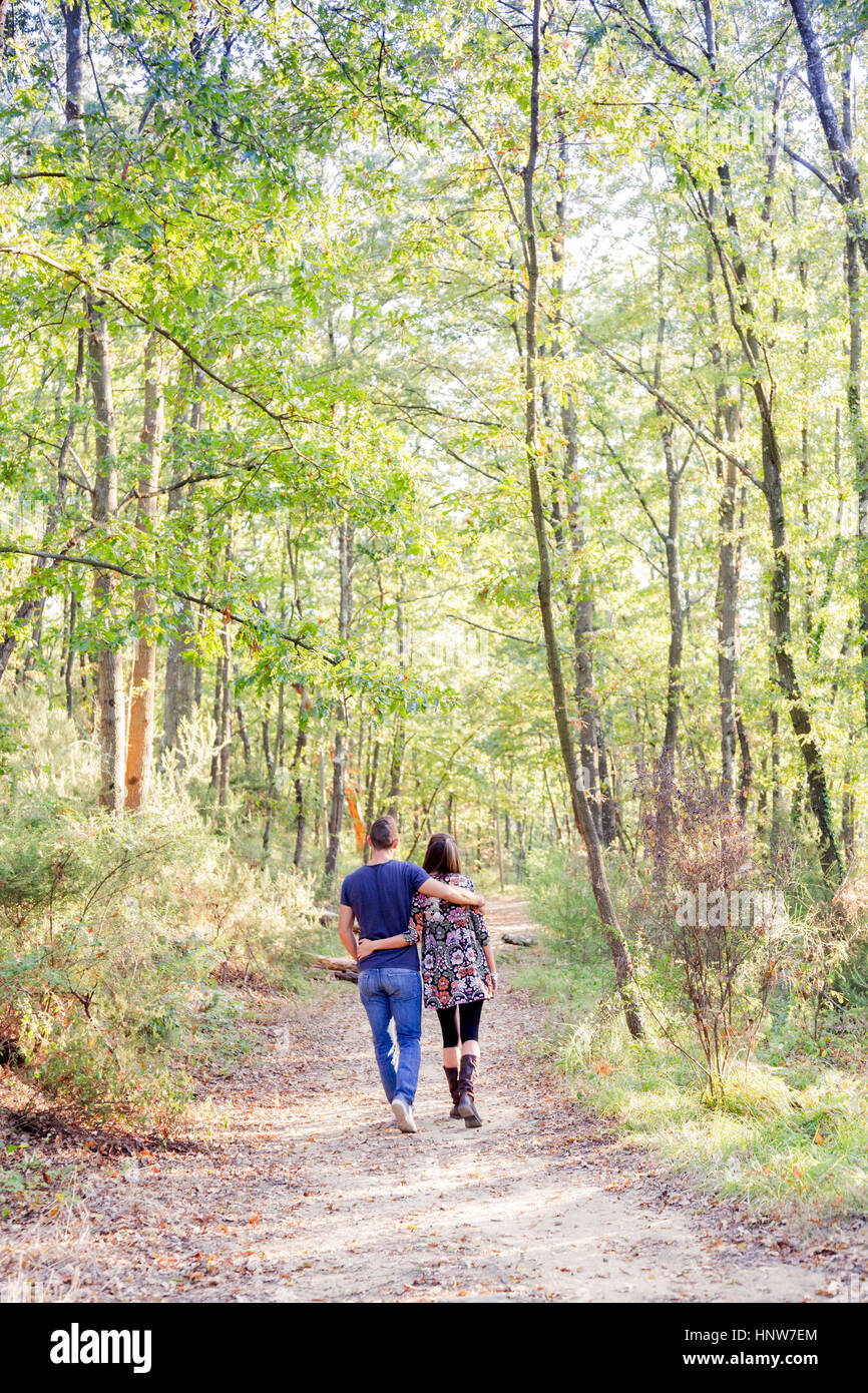 Rear view of couple walking on tree lined path Stock Photo - Alamy