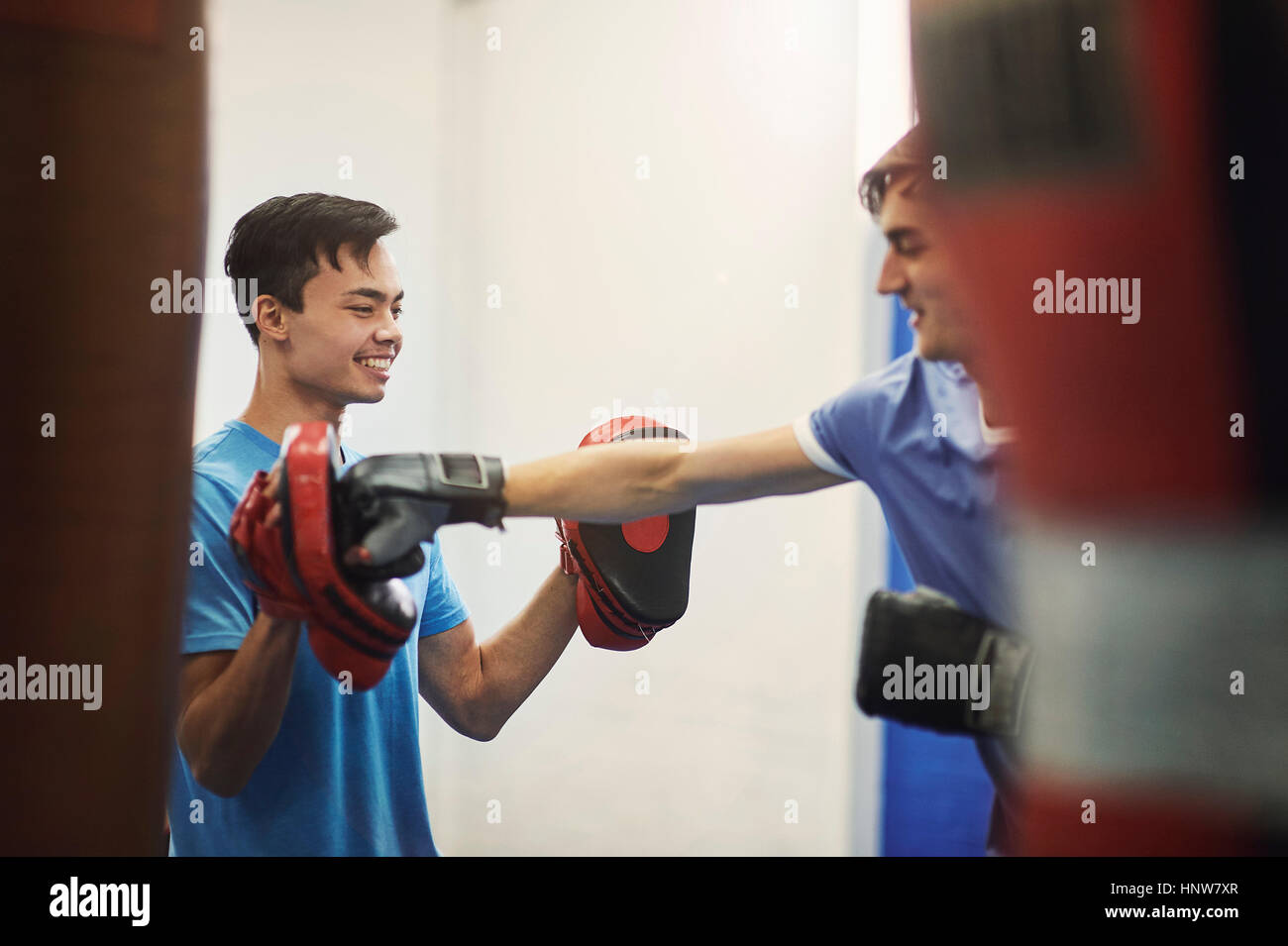 Male boxer training, punching teammate's punch mitt Stock Photo