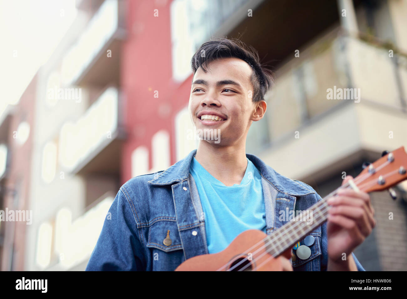 Young man on street playing ukulele Stock Photo