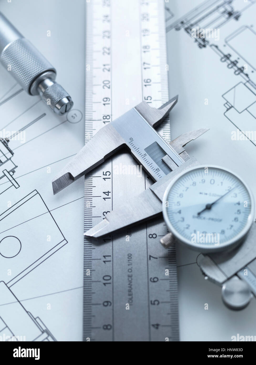 Dial calipers sitting on steel rule with engineering drawings Stock