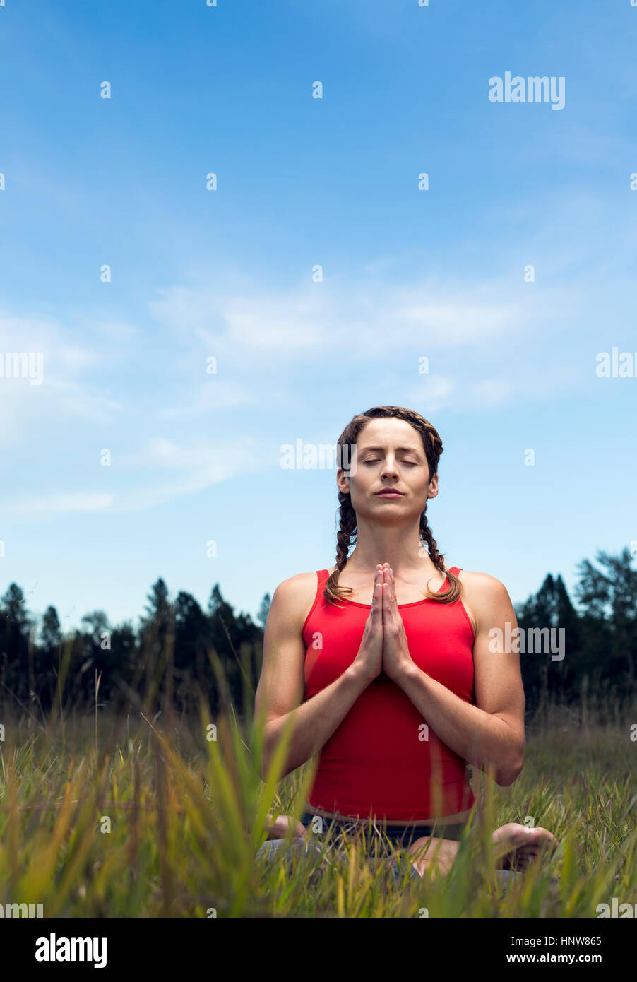 Young woman sitting in field, in yoga position Stock Photo - Alamy