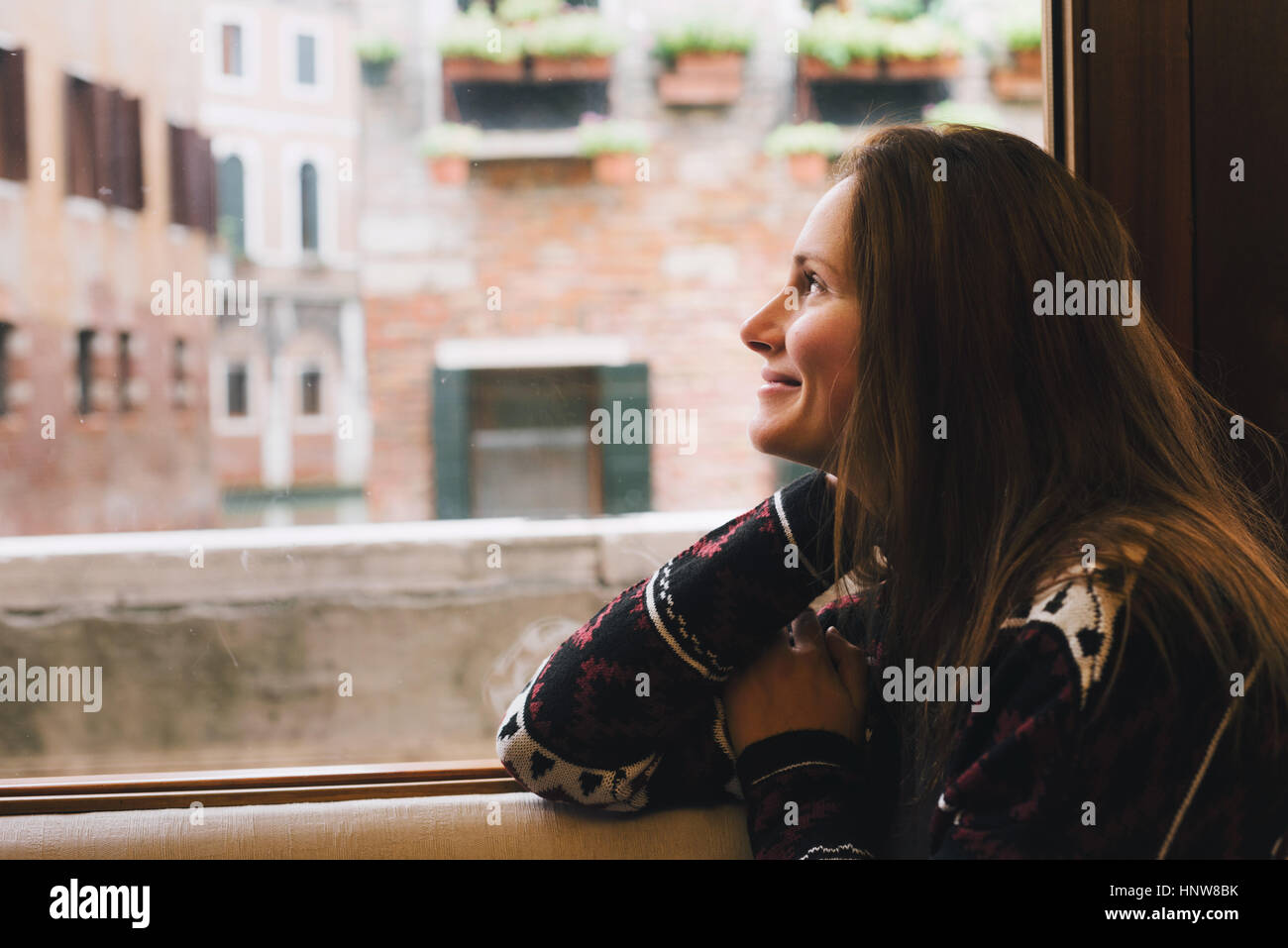 Woman looking out window, Venice, Italy Stock Photo