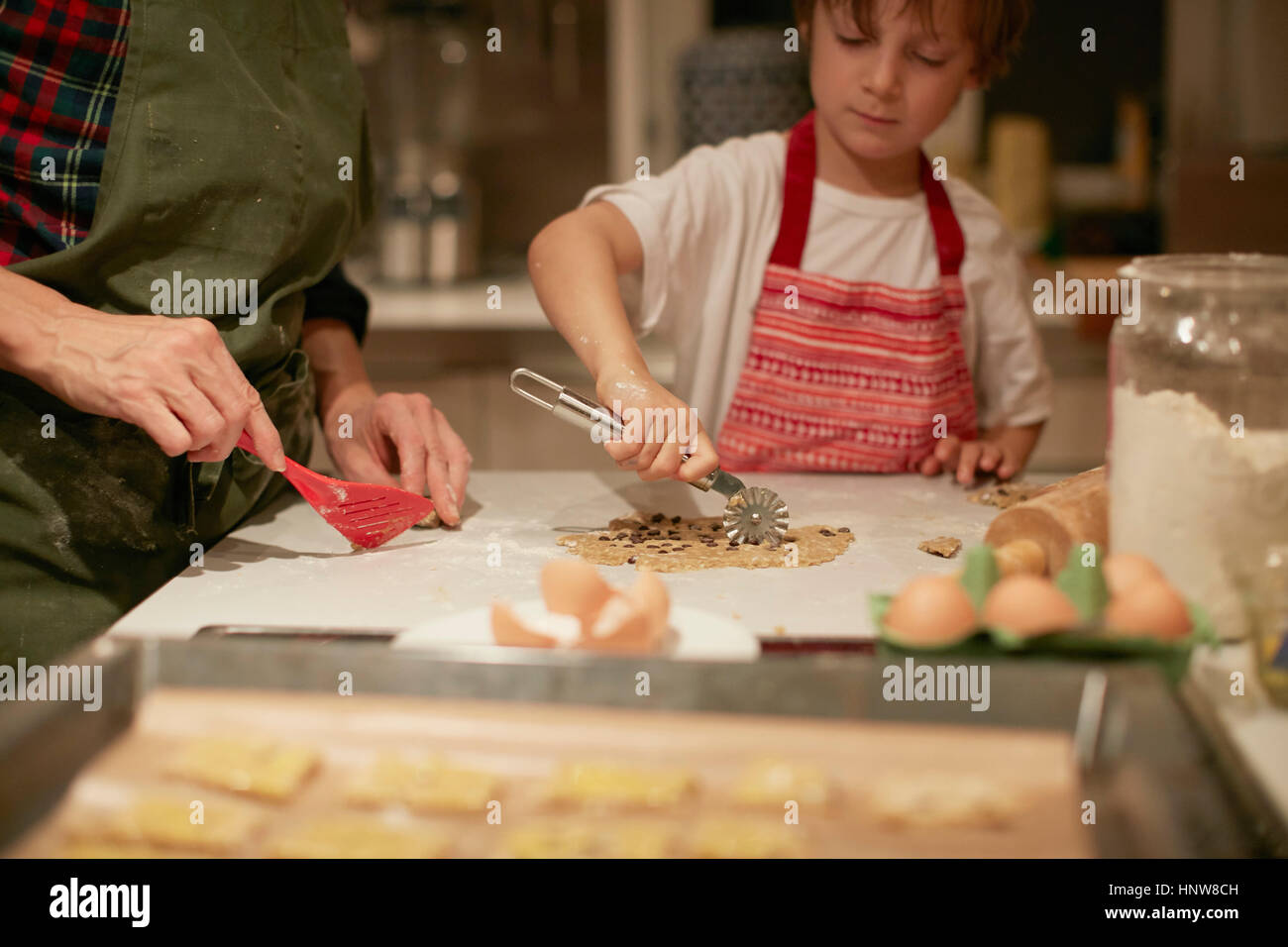 Cropped shot of woman and son cutting dough on kitchen counter Stock Photo
