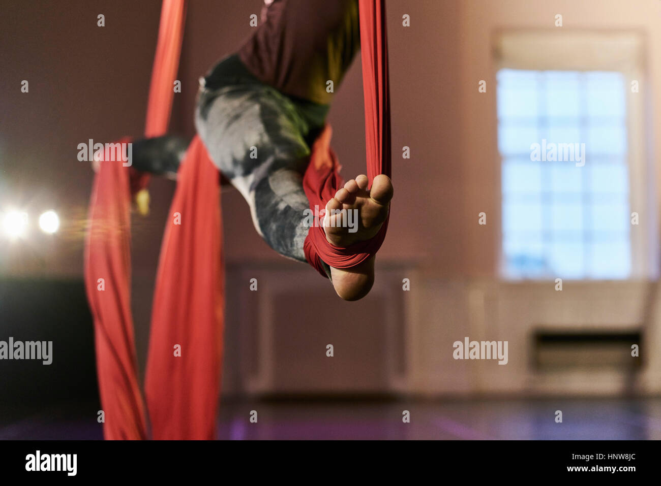 Waist down view of young female aerial acrobat practicing splits on silk rope Stock Photo