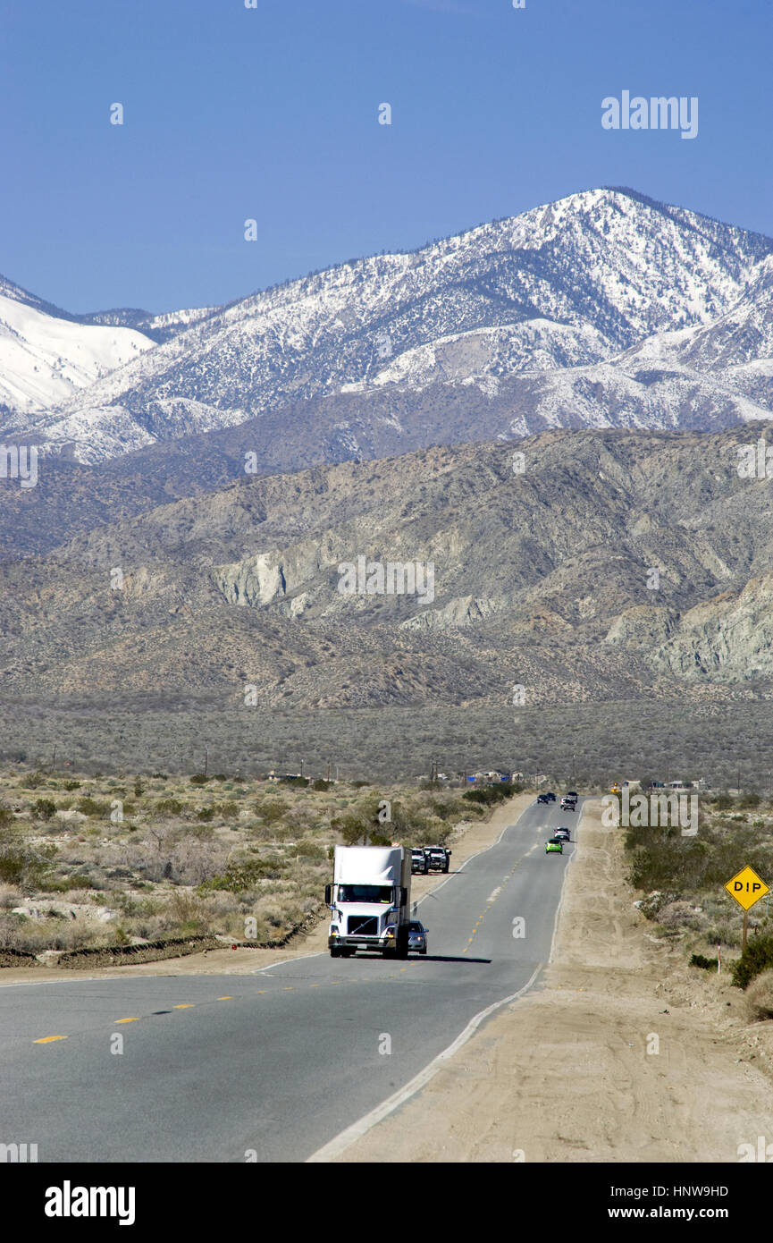 Truck on road in the Palm Desert with mountains with snow near Palm