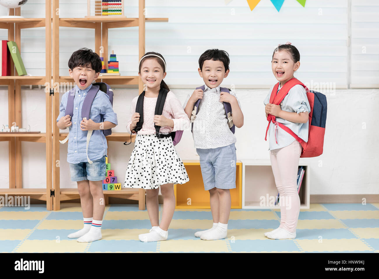 Smiling kindergarten kids with backpacks standing in line Stock Photo