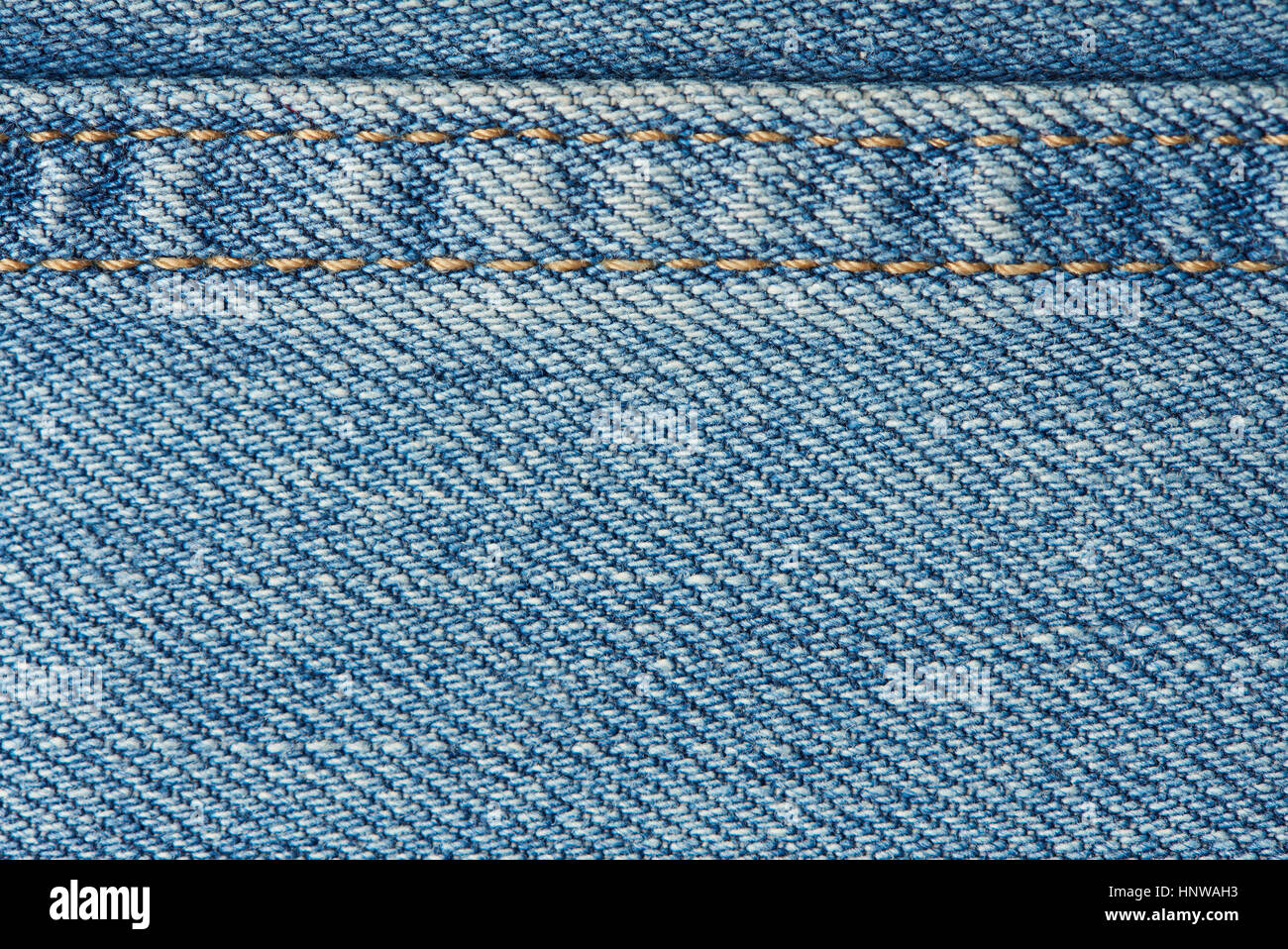 Stitches on light blue jeans background close up Stock Photo
