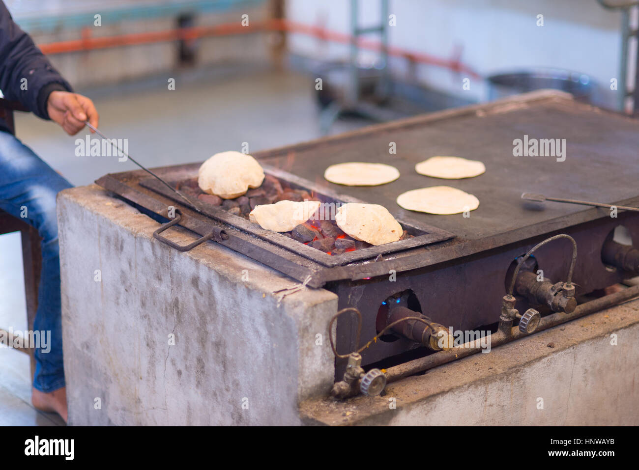 Man cooking Indian flat bread, called chapati, and roasting it on live flame. Stock Photo