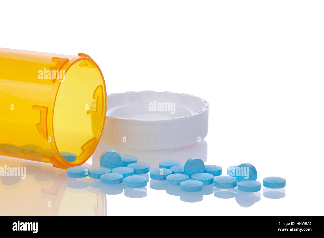 medication bottle on side with blue pills spilling out onto a