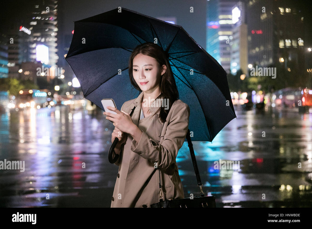 Young woman with umbrella in city at night Stock Photo