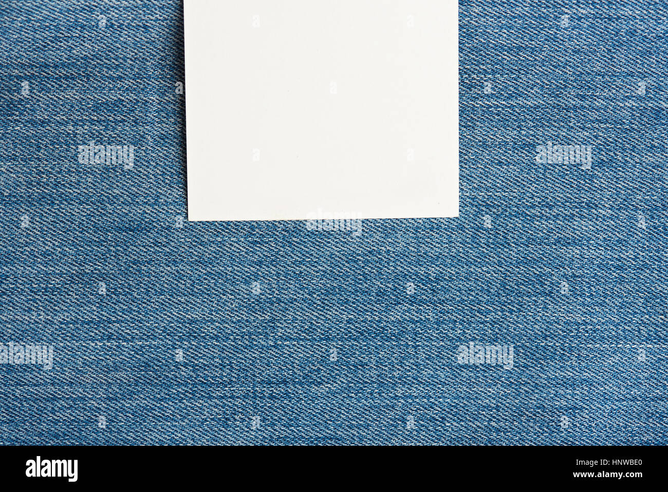 White square label on top of light blue jeans texture Stock Photo