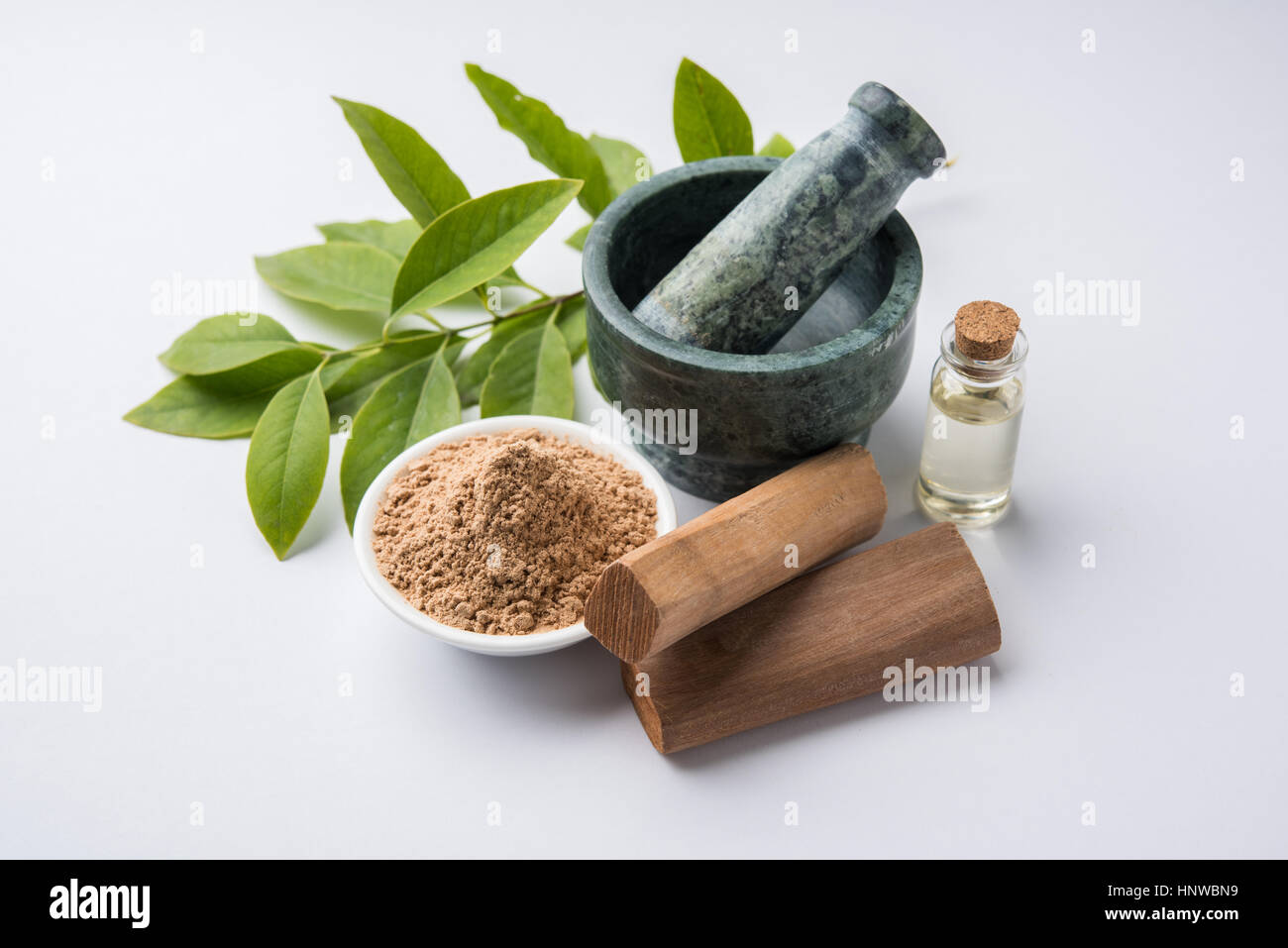 Chandan or sandalwood powder with traditional mortar, sandalwood sticks, perfume or oil and green leaves. selective focus Stock Photo