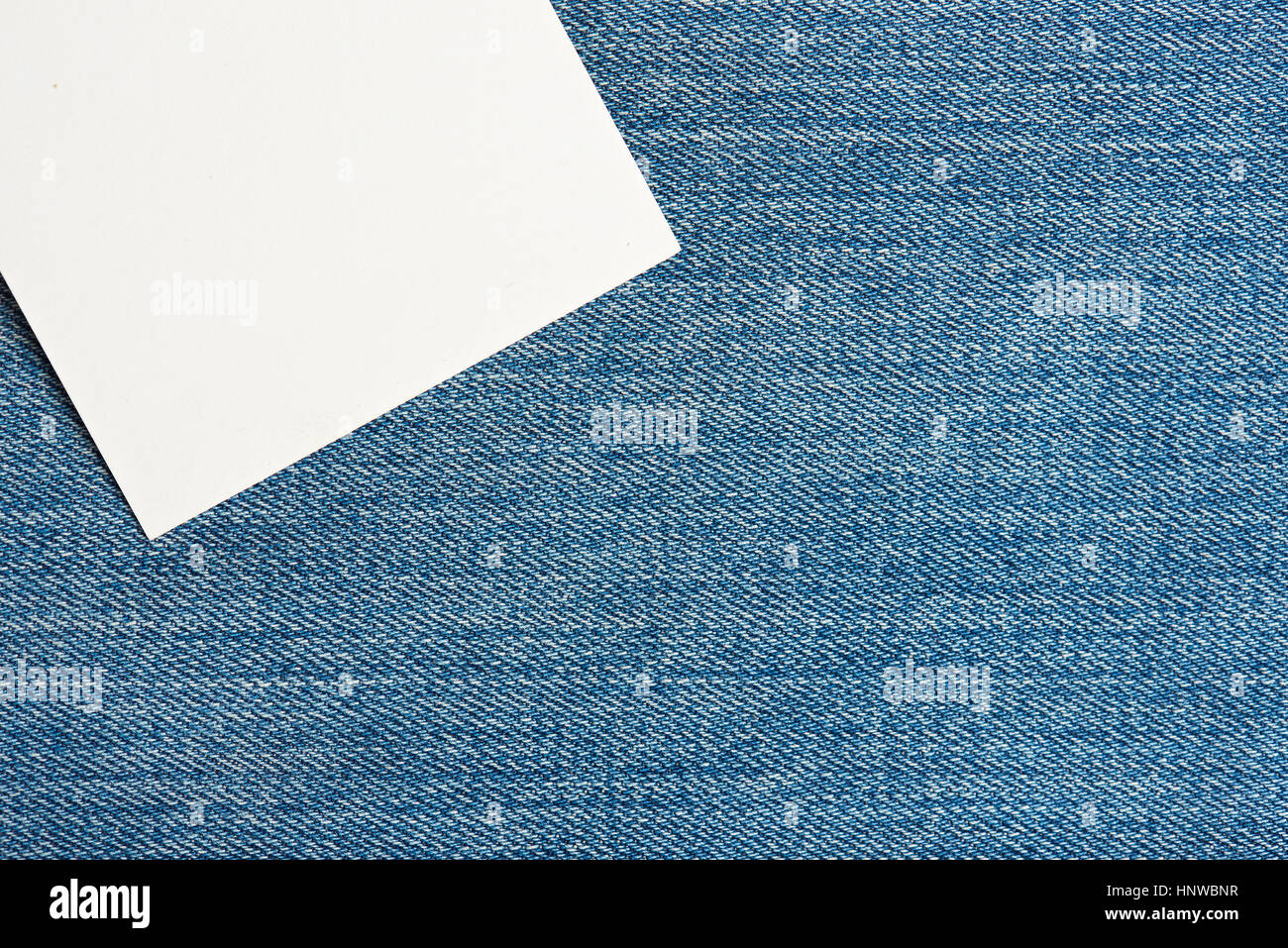 White tag on light blue jeans textile texture surface  background Stock Photo