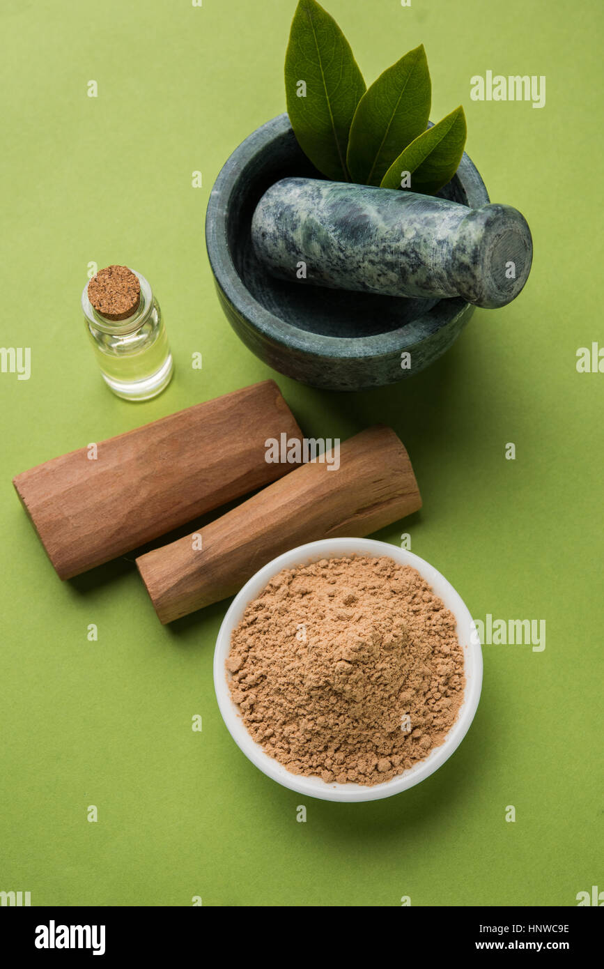 Chandan or sandalwood powder with traditional mortar, sandalwood sticks, perfume or oil and green leaves. selective focus Stock Photo