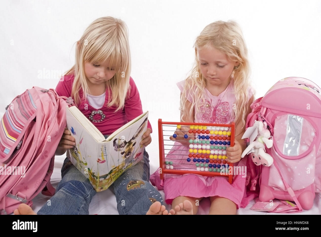 Model release, Zwei Schulmaedchen mit Lesebuch und Abakus - two schoolgirls with book and abacus Stock Photo