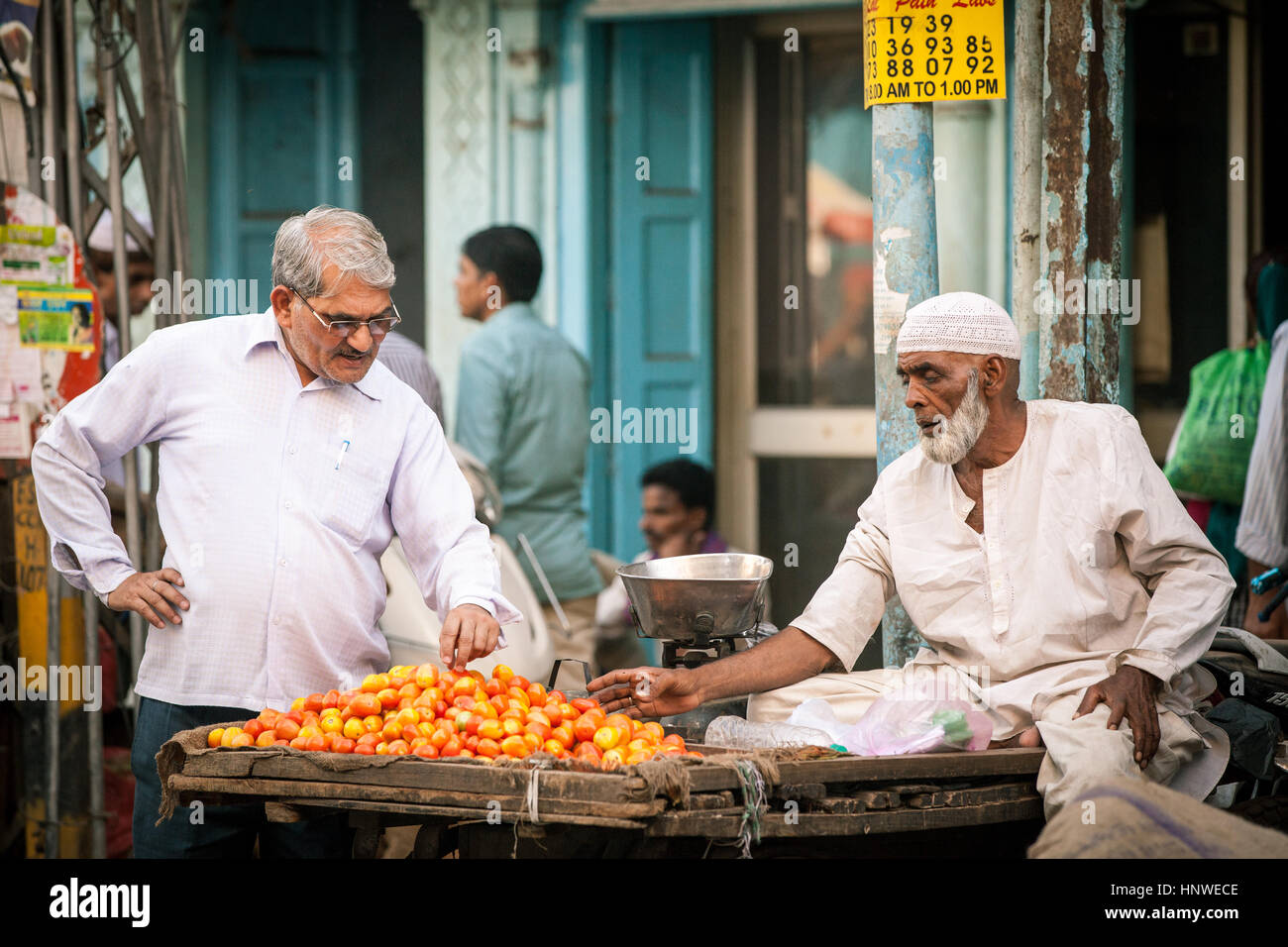Delhi, India - September 18, 2014: Indian man buying tomatoes from muslim vendor on the street of Old Delhi, India on September 18, 2014. Stock Photo
