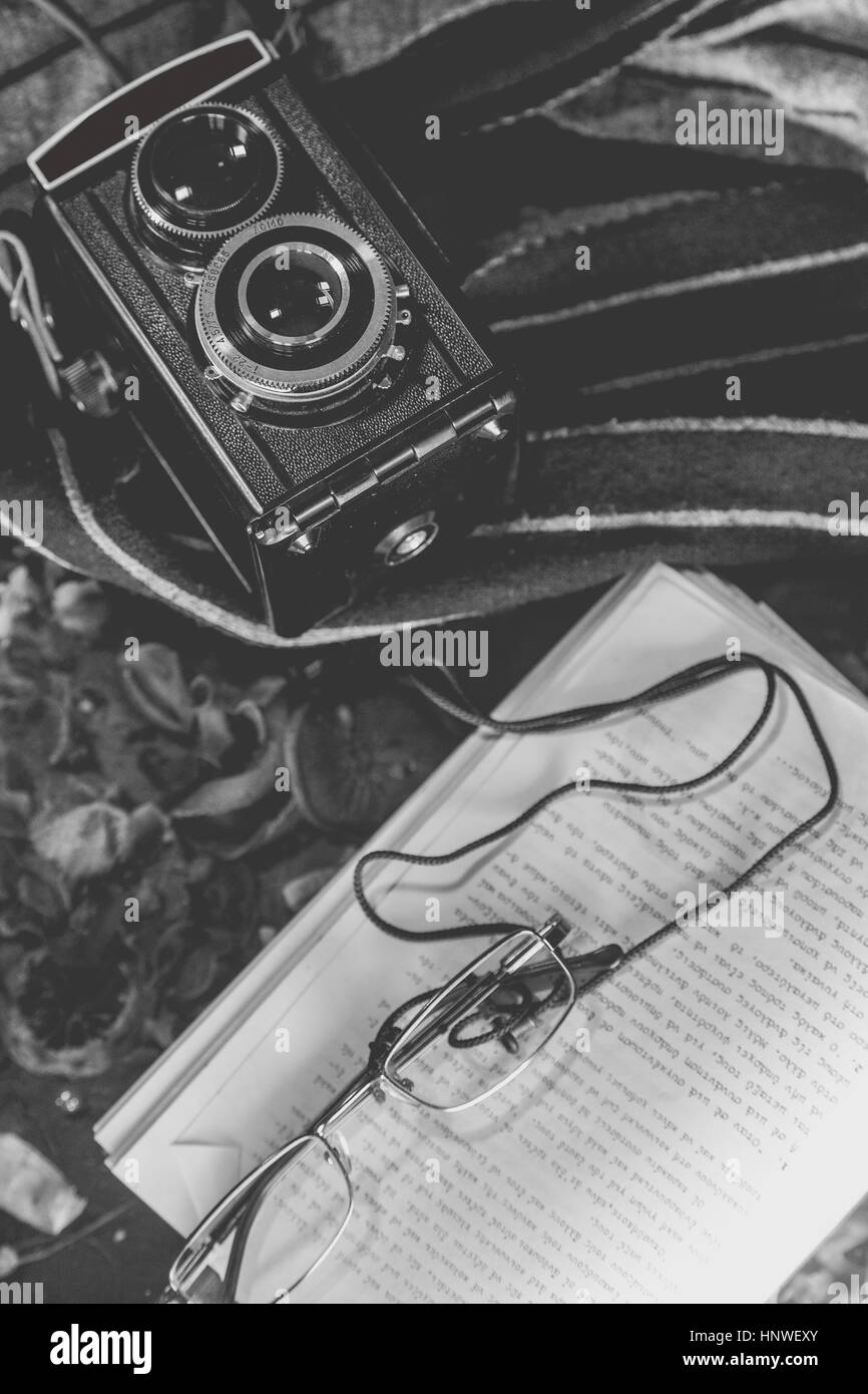 Top view of film camera a book and eyeglasses on top of the book black and white artistic concept Stock Photo