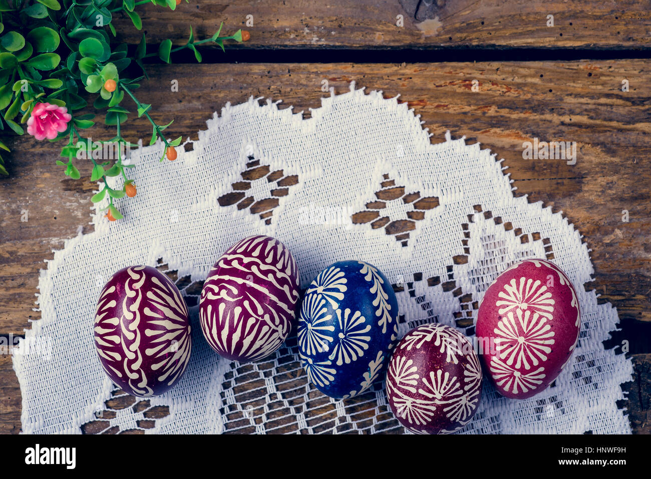 Hand-painted easter eggs, colorised, on the wooden table and embroidered napkin Stock Photo