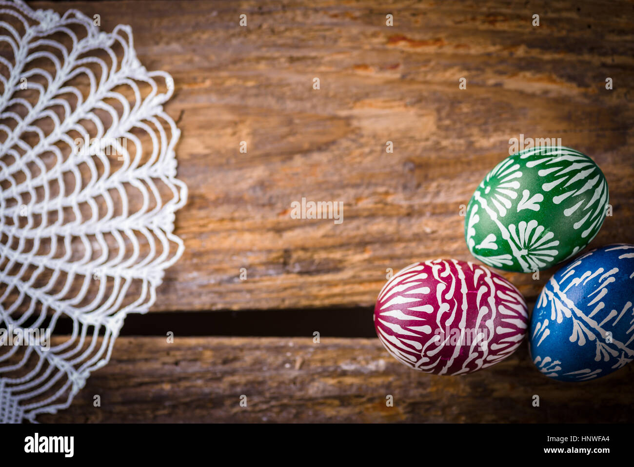 Hand-painted easter eggs, colorised, on the wooden table and embroidered napkin Stock Photo