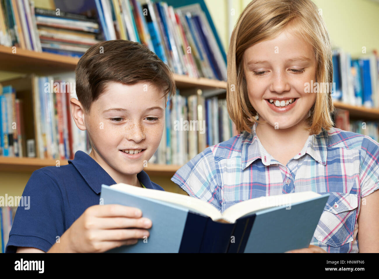 Two School Pupils Reading Book In Library Stock Photo