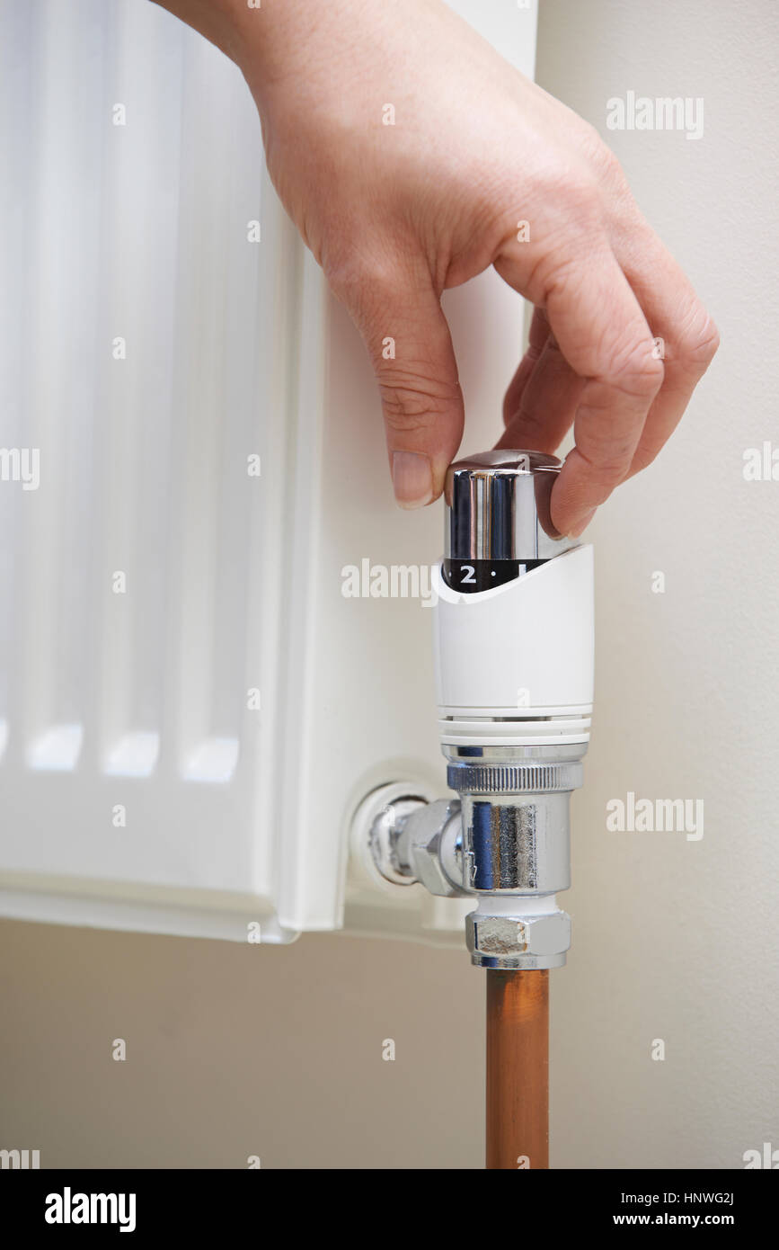 Close Up Of Hand Adjusting Heating Thermostat Stock Photo