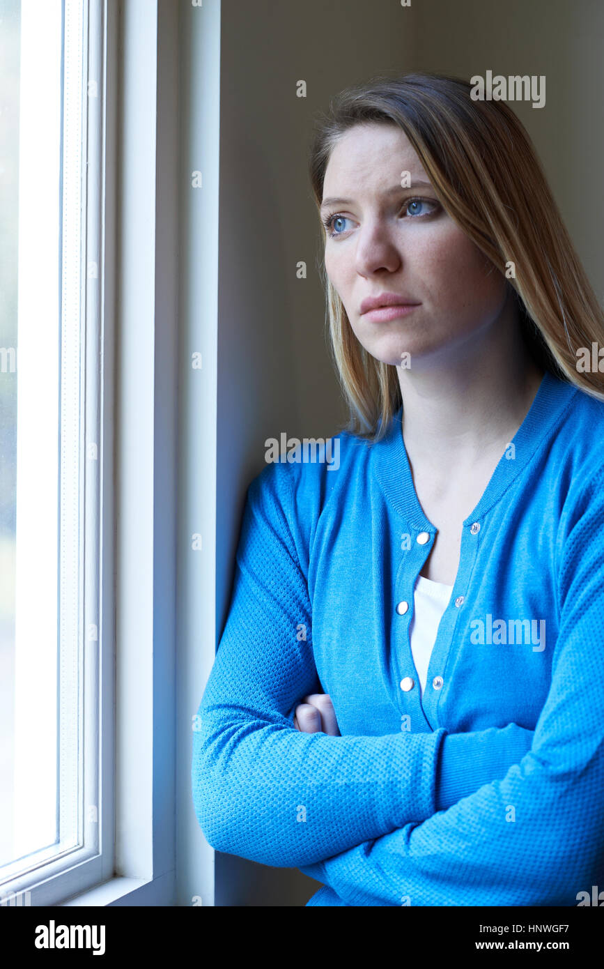 Sad Woman Suffering From Depression Looking Out Of Window Stock Photo