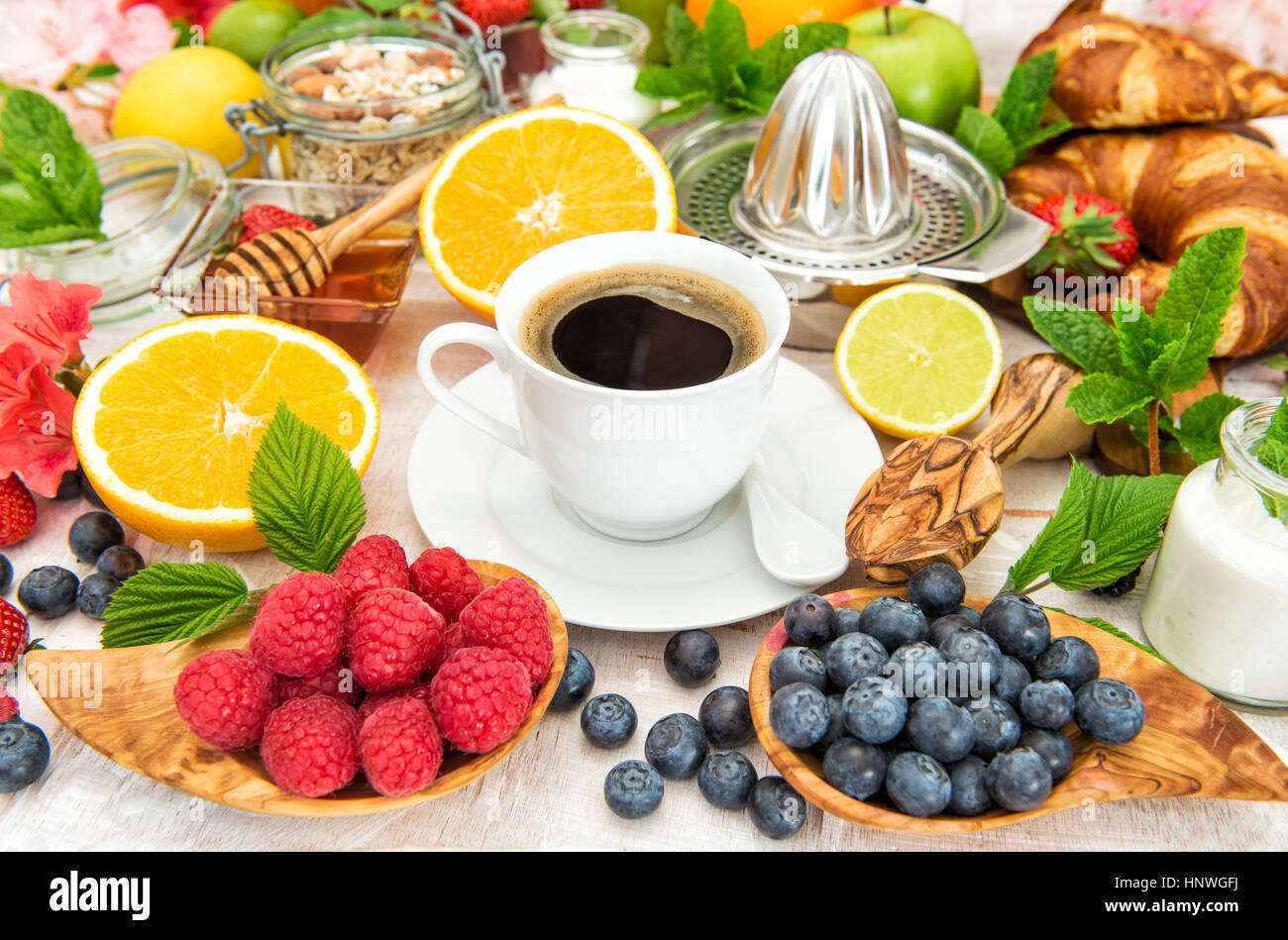 Breakfast with coffee, croissants, muesli, fresh fruits, berries, orange, apple, milk. Healthy food concept Stock Photo