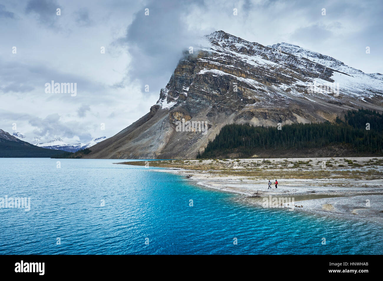 Hikers hiking by lake and snow capped mountains, Banff, Alberta, Canada Stock Photo