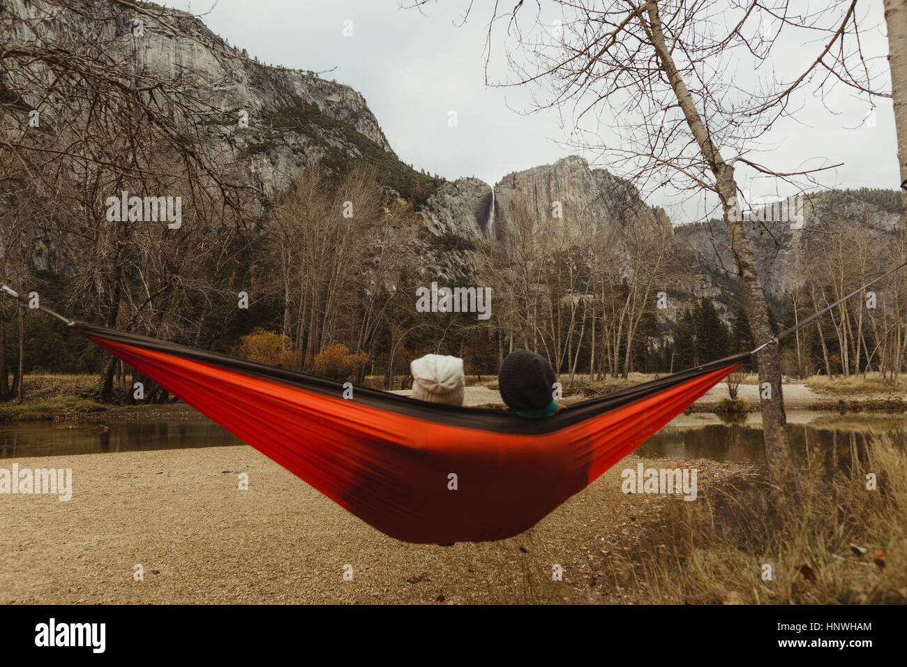 Rear view of couple reclining in red hammock looking out at landscape, Yosemite National Park, California, USA Stock Photo