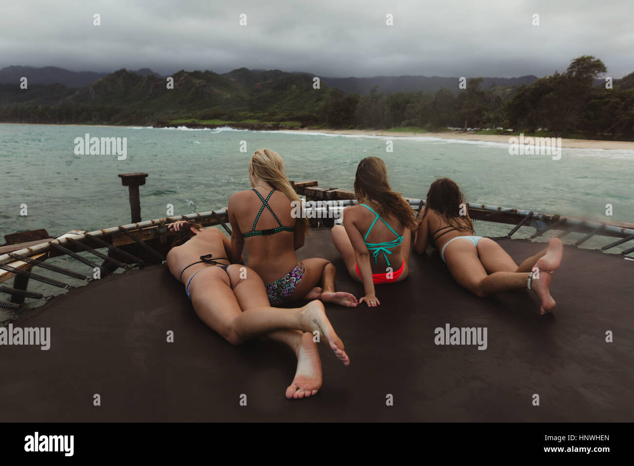 Rear view of friends wearing bikinis relaxing on trampoline in sea, Oahu, Hawaii, USA Stock Photo