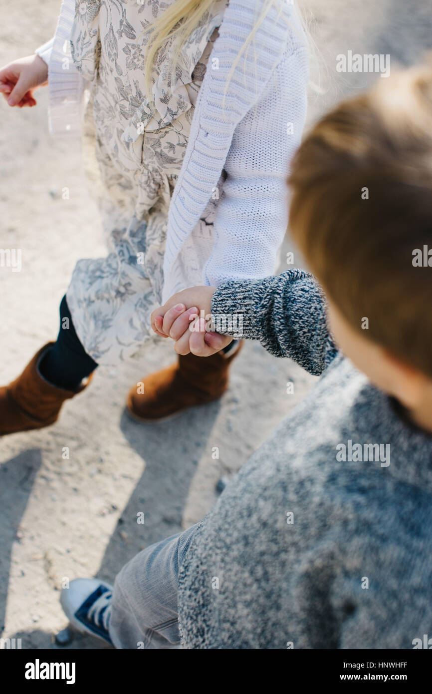 Siblings holding hands walking on gravel road Stock Photo - Alamy