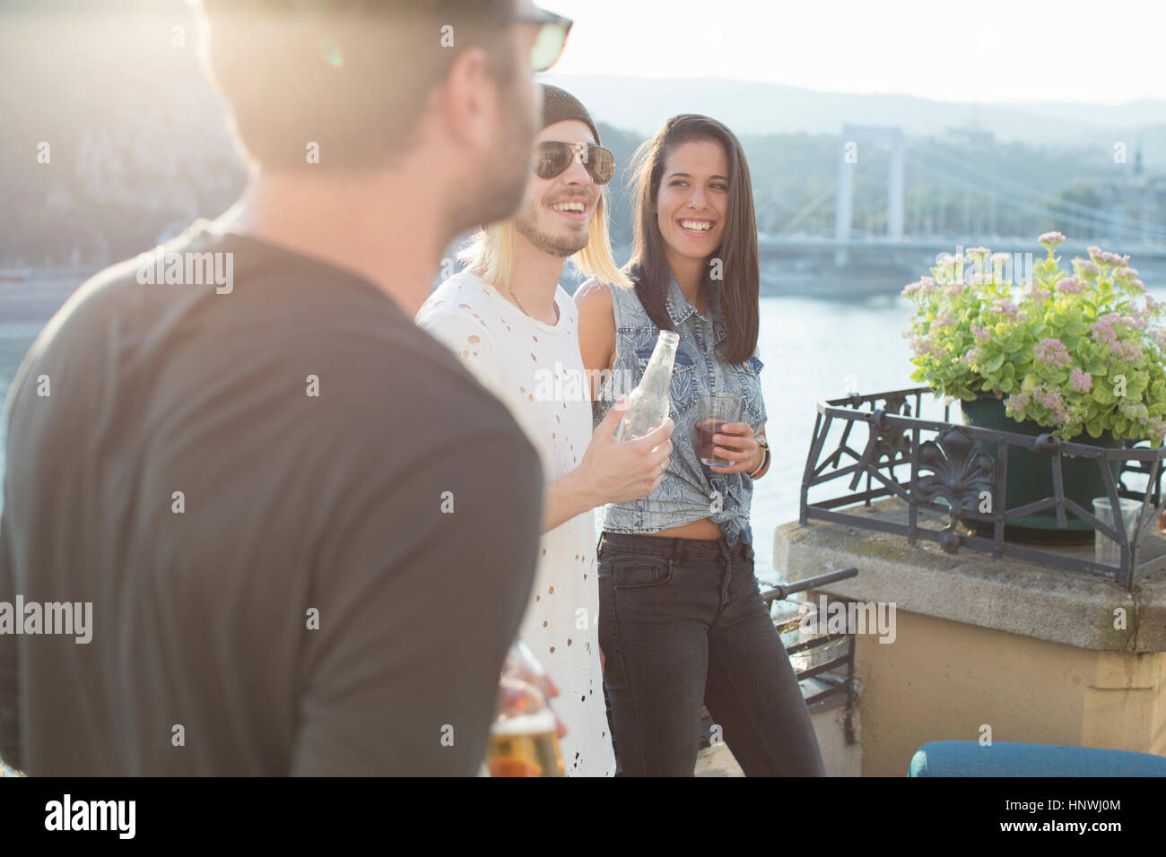 Three adult friends partying on waterfront roof terrace, Budapest, Hungary Stock Photo