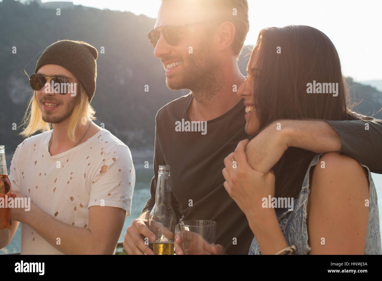 Adult friends partying on sunlit waterfront roof terrace Stock Photo