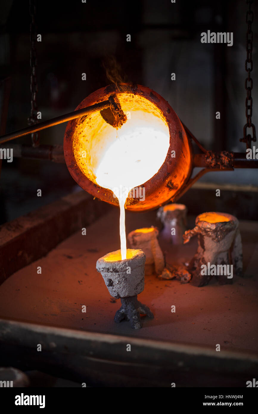 Molten bronze being poured from pot in foundry Stock Photo