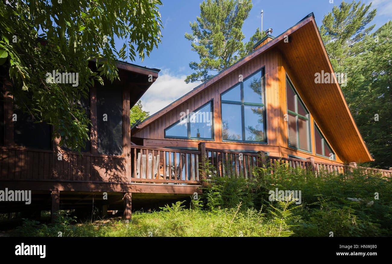 Back view of a milled cottage style flat log profile home with elevated wooden deck, Mt-Tremblant, Quebec, Canada Stock Photo