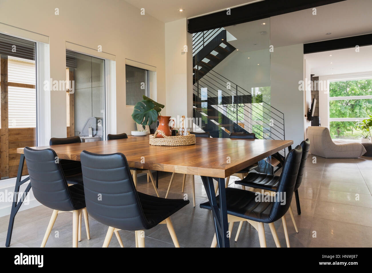 American walnut wood dining table and black leather chairs in the dining  room inside a modern cube style home, Quebec, Canada Stock Photo - Alamy
