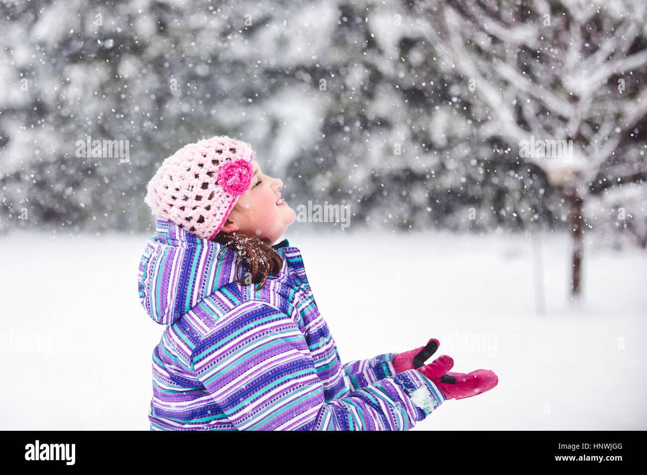 Girl cupping hands to catch falling snow Stock Photo